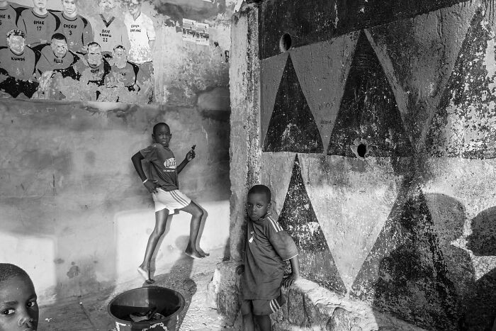 Black and white portrait of children playing by a textured wall with geometric patterns, powerful photographs of children worldwide.