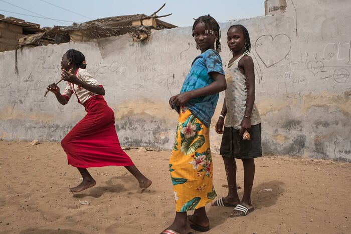 Three children of the world playing outside by a wall with drawings, captured in powerful photographs by Andrea Torrei