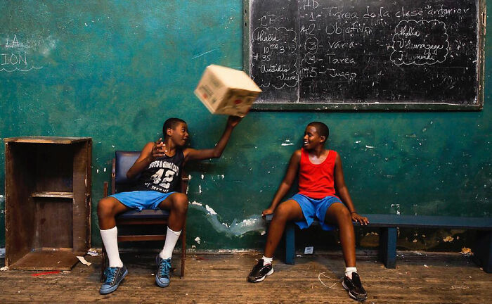 Two children playing with a box in a classroom, captured in powerful photographs by Andrea Torrei showcasing children of the world.