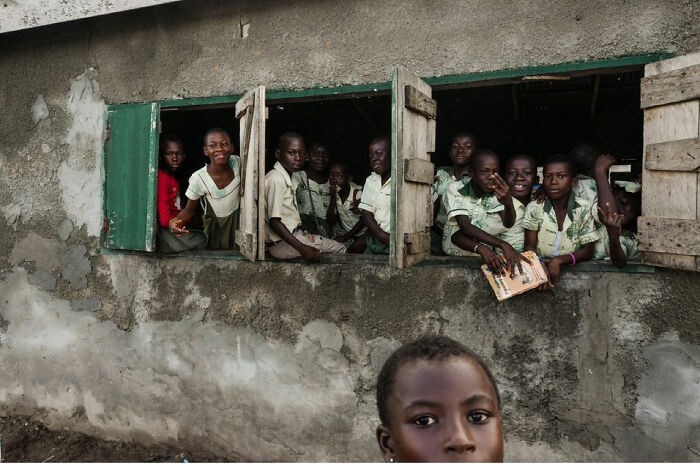 Group of children of the world in a classroom, captured in a powerful photograph by Andrea Torrei showing diverse young faces.