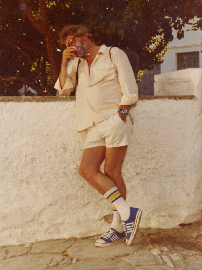 Vintage vacation photo of a man in shorts and sneakers leaning against a wall, capturing a moment before cell phone cameras.