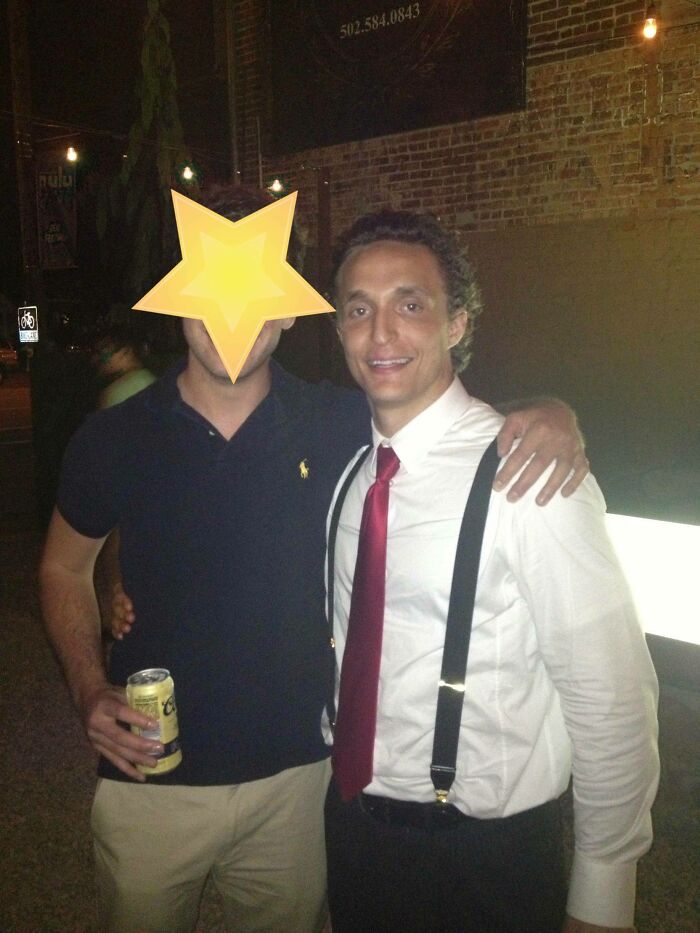Man posing with a Johnny Derp look-alike in suspenders and a red tie, captured during a nighttime outdoor event.