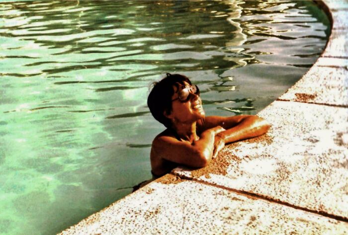 Person wearing glasses relaxing in a pool on a vintage vacation photo from before cell phones had cameras.