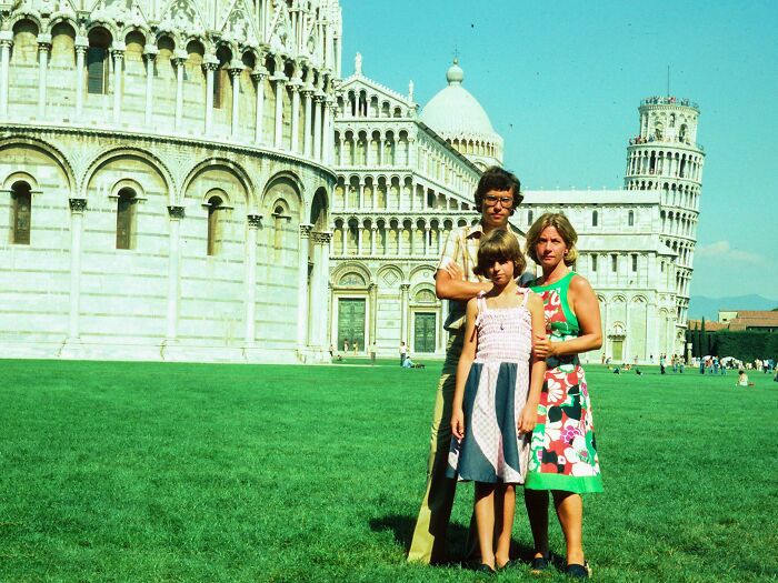 Family posing for vacation photo near the Leaning Tower of Pisa in a vintage image before cell phones had cameras.