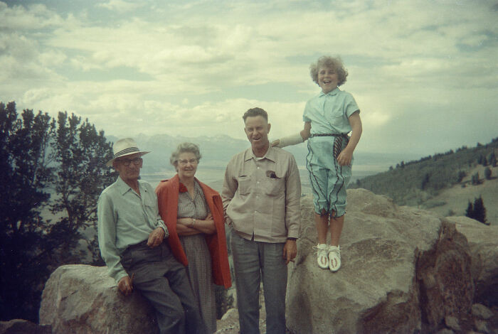 Vintage vacation photo of a family posing on rocks in a mountainous landscape before cell phone cameras existed.