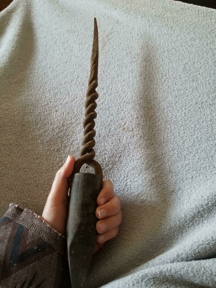Hand holding a twisted metal object, an old artifact found with no clue, illustrating people finding something old.
