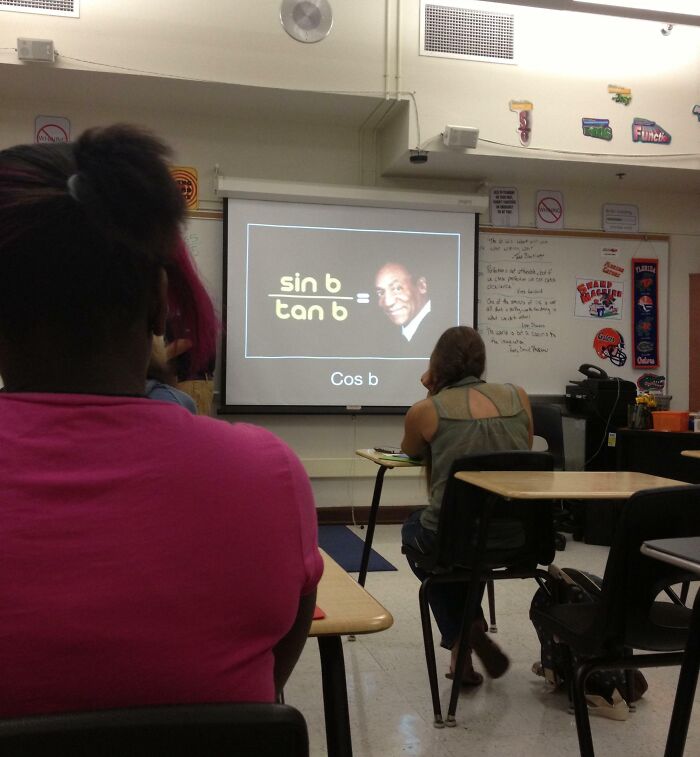 Classroom with students watching a funny teacher's math presentation featuring a humorous equation and Bill Cosby photo.