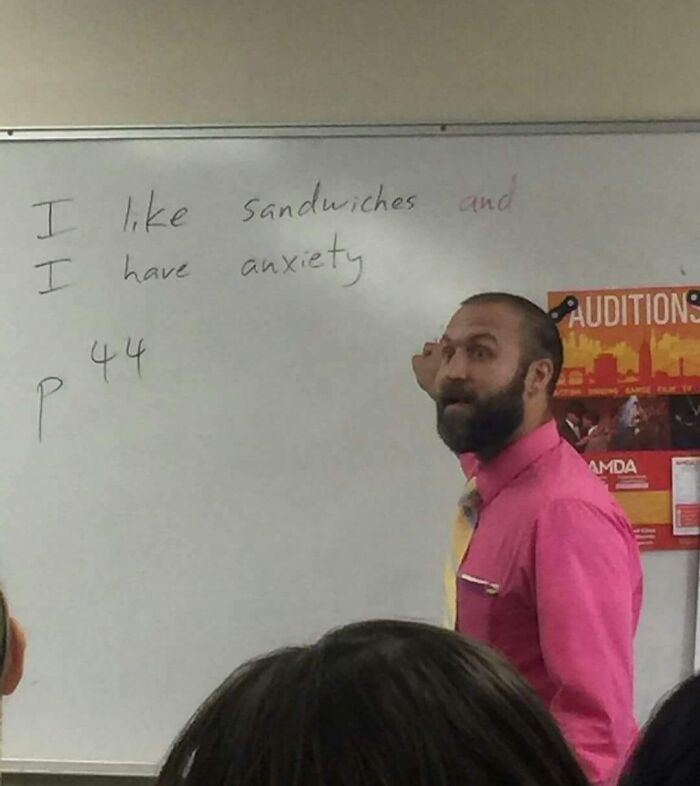 Teacher in pink shirt writing a funny message on the whiteboard showing humor in the classroom setting.