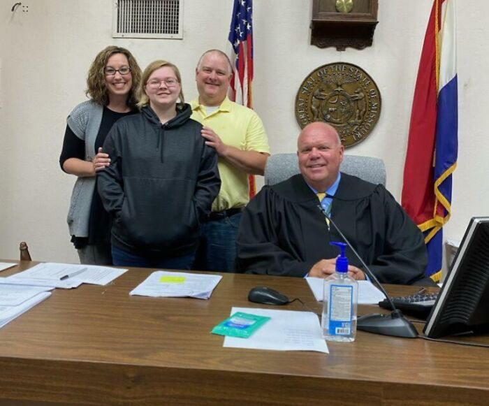 A family posing with a judge in a courtroom, capturing a funny and wholesome parenting moment shared by kids.