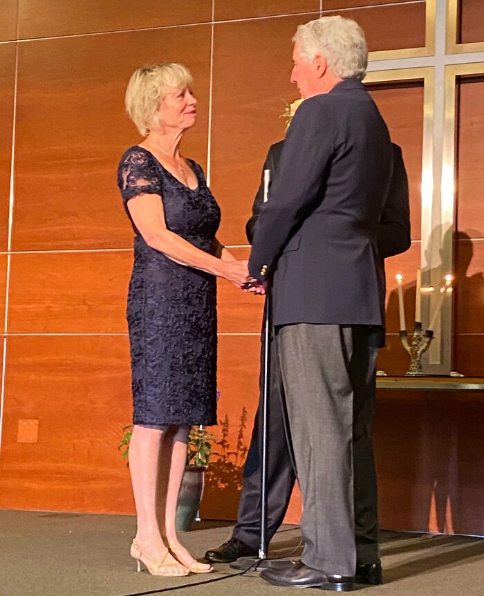 Older couple holding hands during a ceremony, capturing a funny and wholesome parents moment shared by kids.