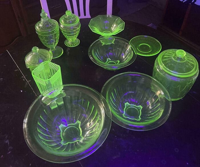 Glowing vintage glassware set on a dark table, showcasing bright green hues under UV light in a wholesome family setting.