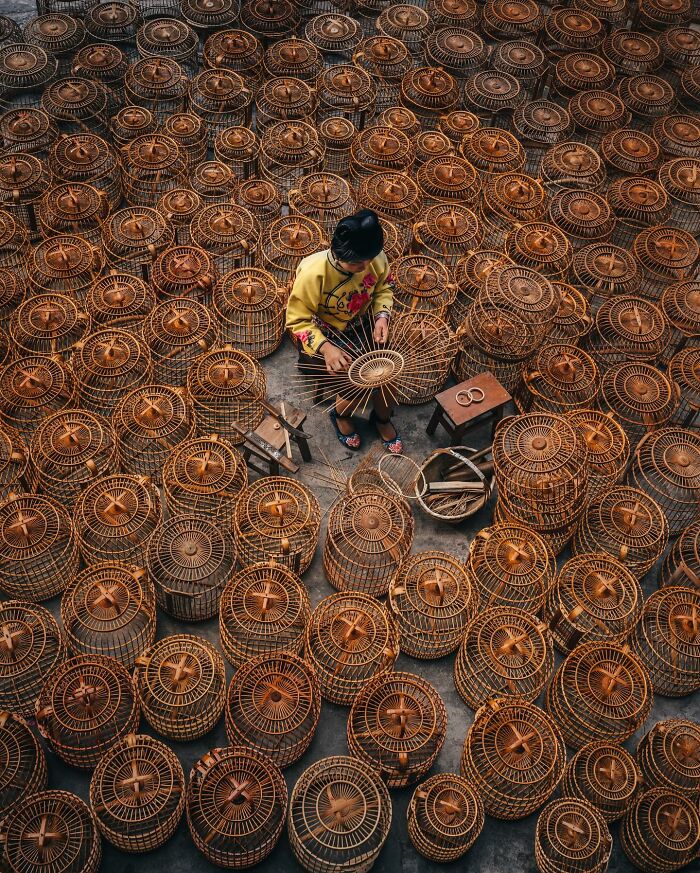 Person weaving traditional bamboo birdcages surrounded by numerous finished cages, glimpses of everyday life in Asia.