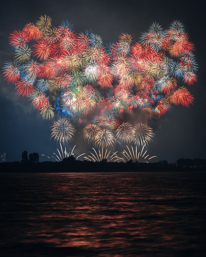 Colorful fireworks lighting up the night sky over water, capturing vibrant moments of everyday life in Asia.
