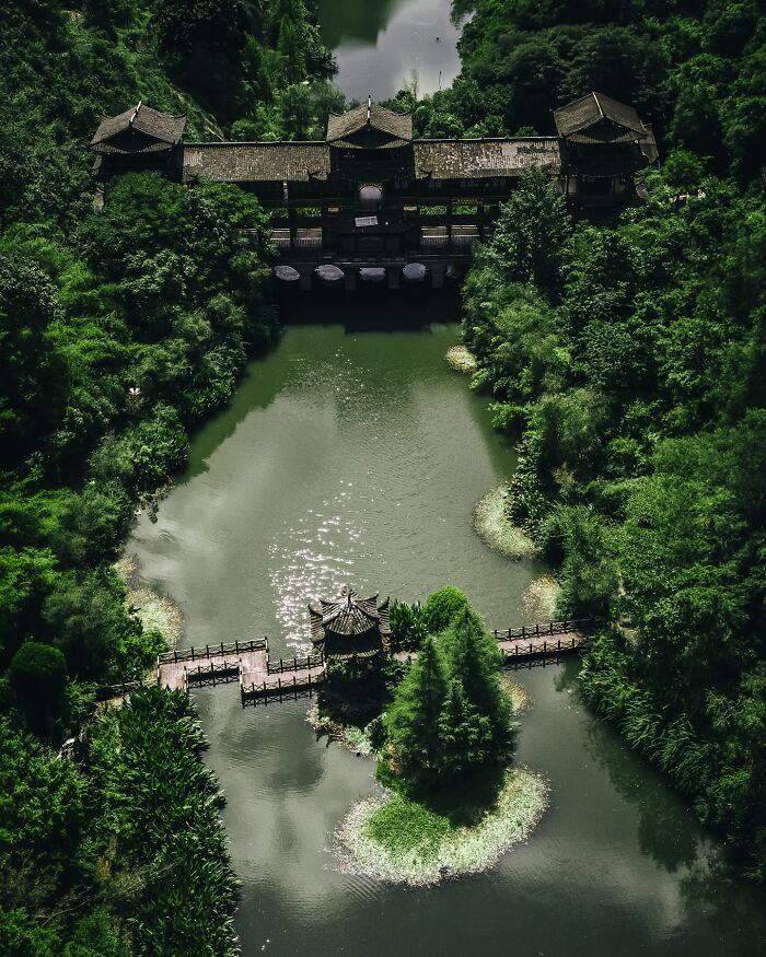 Aerial view of traditional Asian architecture surrounded by lush greenery and calm water, showcasing glimpses of everyday life in Asia.