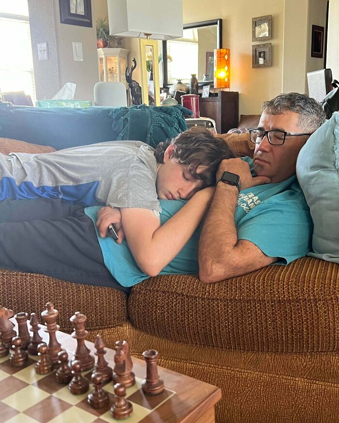 A father and son napping together on a couch in a cozy living room, showcasing funny and wholesome parent moments.