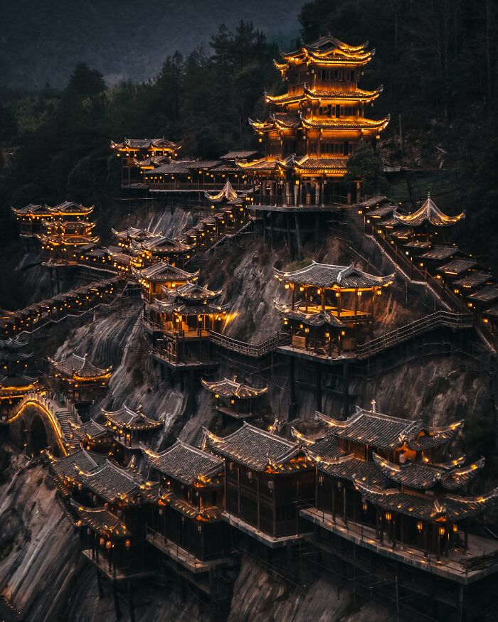 Traditional Asian architecture illuminated at night on a steep mountainside, showcasing everyday life in Asia.