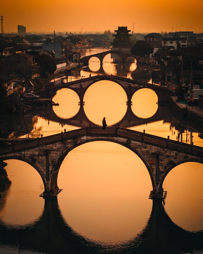 Ancient bridges at sunset reflecting on calm water, capturing mesmerizing glimpses of everyday life in Asia.