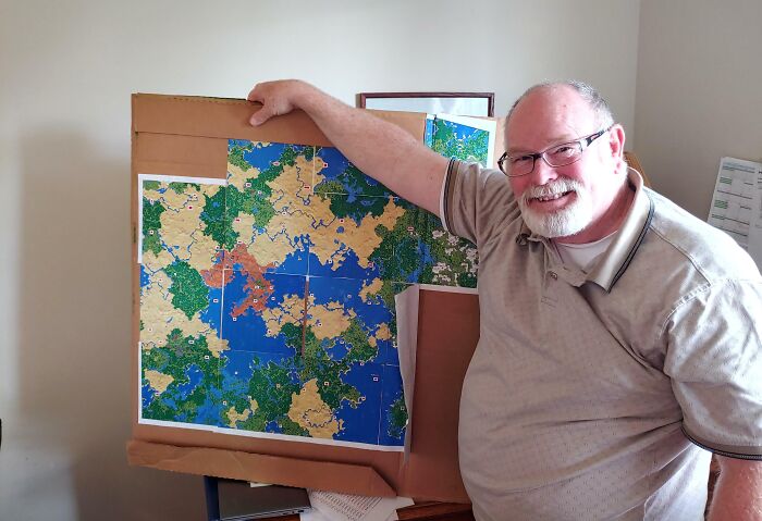 Smiling father proudly shows colorful game map, capturing funny and wholesome moments parents share with their kids.