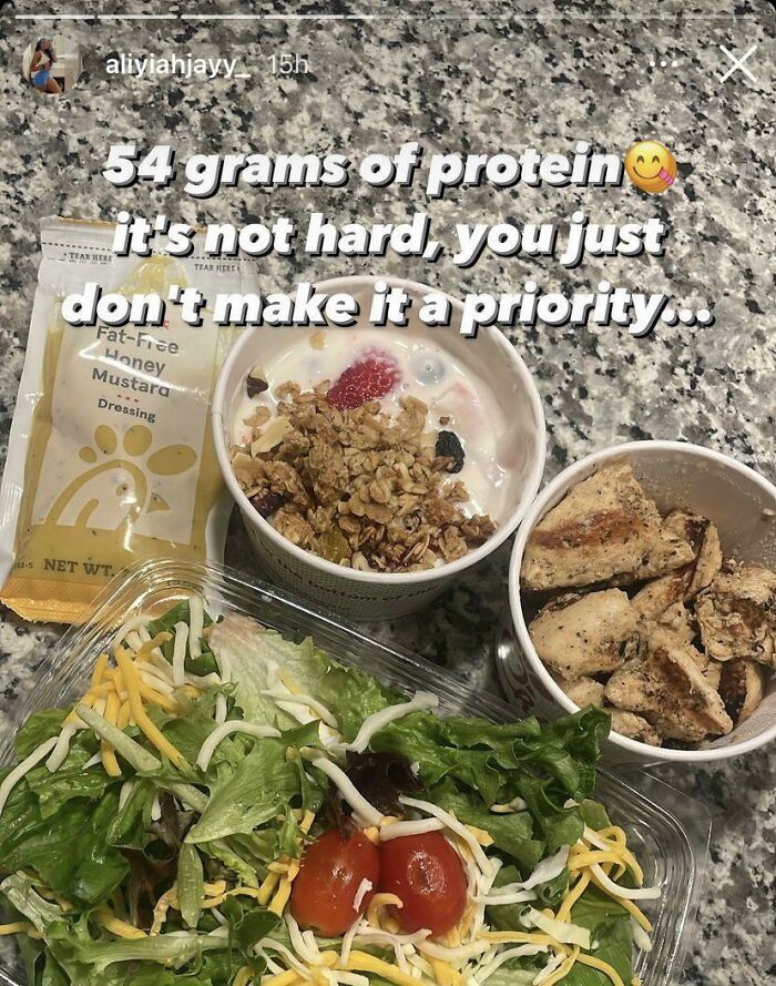 Protein-packed meal with grilled chicken, salad, granola yogurt, and fat-free honey mustard dressing on a granite countertop