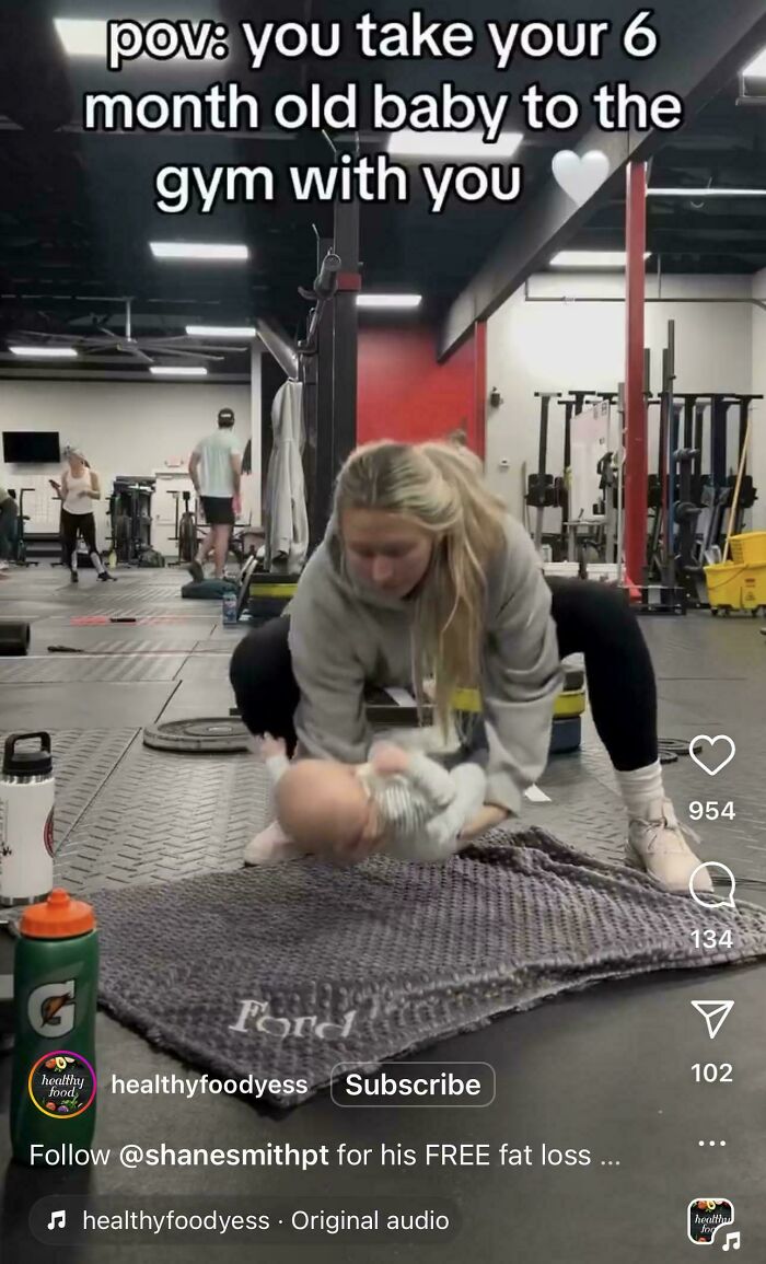 Woman taking her 6-month-old baby to the gym, demonstrating fitness with baby in an unconventional workout setting.