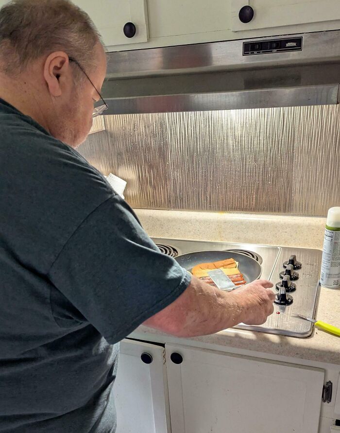 Man cooking hot dogs and pancakes on stove, capturing funny and wholesome moments parents share with kids.