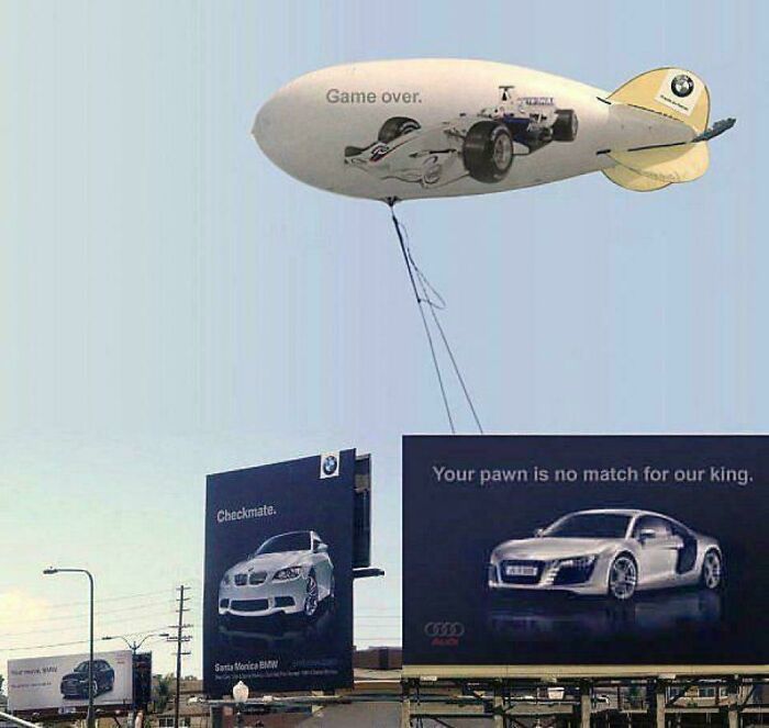 Funny and weird billboards showing a BMW and Audi rivalry with a blimp and multiple car ads in the cityscape.