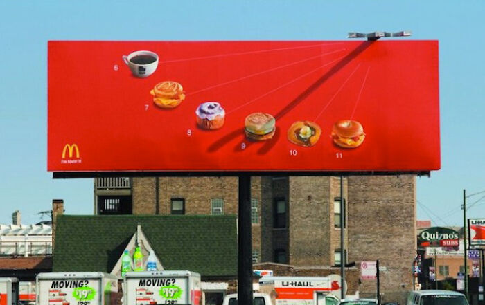 Funny and weird billboard showing McDonald's breakfast items with numbers against a bright red background in an urban setting.