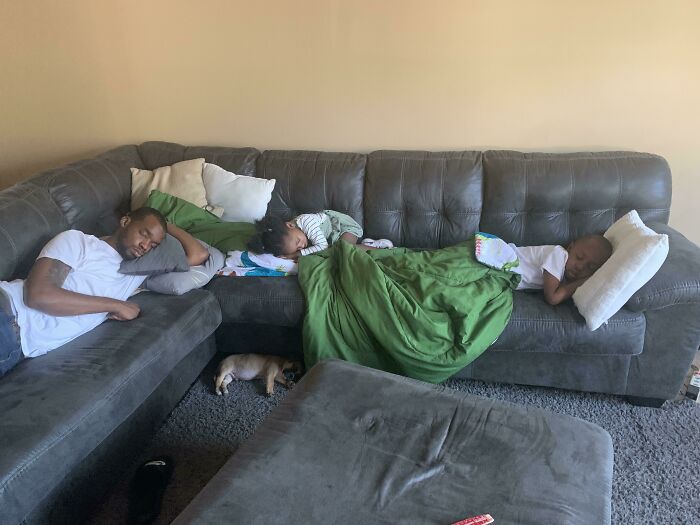 Family napping on a couch with kids, illustrating funny photos revealing the differences between moms and dads.