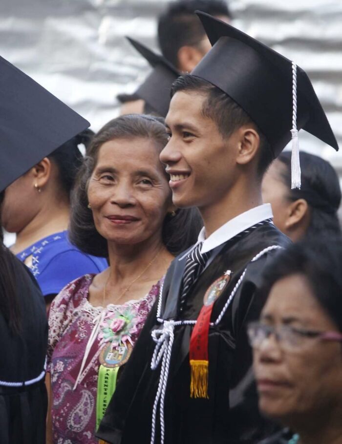 A proud parent smiling warmly at their graduating child during a cap and gown ceremony, capturing wholesome family moments.