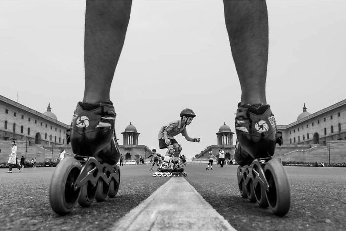 Close-up of roller skates on a street with people skating and historic buildings, capturing everyday life in India.