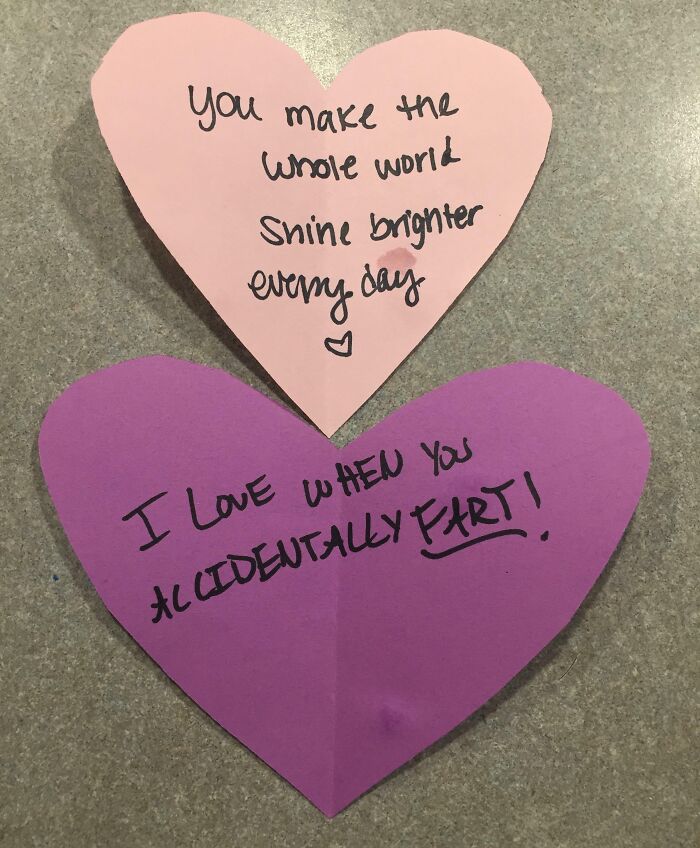 Two heart-shaped notes with contrasting loving messages, highlighting the funny differences between moms and dads.