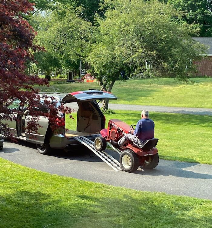 Man loading a riding lawn mower into a van showcasing funny photos revealing the stark differences between moms and dads