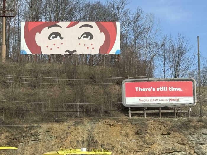 Two funny and weird billboards by Wendy’s, one with a cartoon face and another with the message There’s still time.