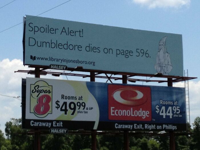 Funny and weird billboard showing a spoiler alert about Dumbledore alongside hotel room advertisements off Caraway Exit.