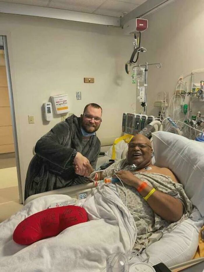 Patient in hospital bed with a red cast shaking hands with visitor, showcasing inspiring facts of kindness and recovery.