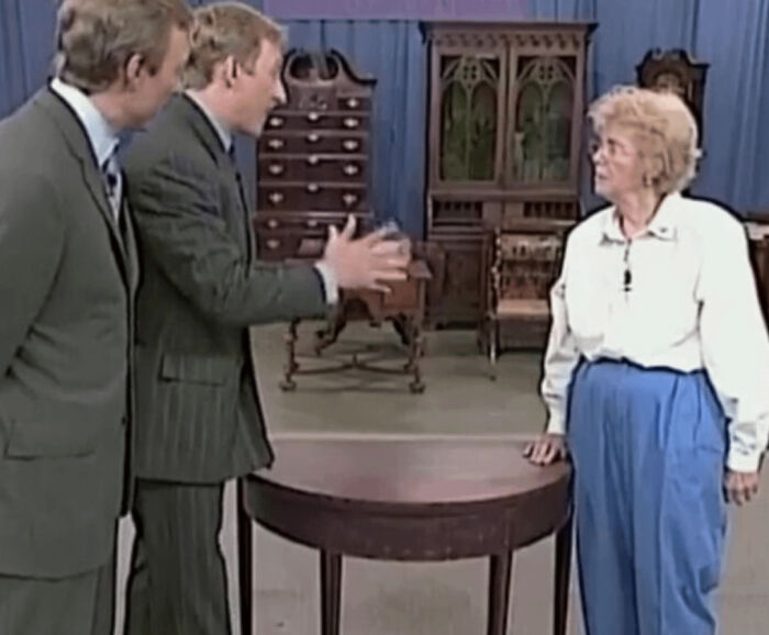 Three people in a discussion around a table in a room filled with antique furniture highlighting inspiring facts.
