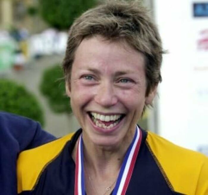 Smiling woman wearing a medal and sports jacket, radiating joy and inspiring facts better than watching the news