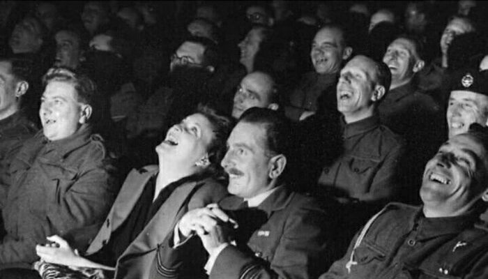 Audience in vintage military uniforms laughing together, illustrating inspiring facts that uplift more than watching the news.