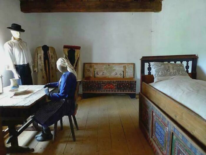 Mannequins in traditional clothing seated and standing in a rustic room showcasing inspiring facts about history and culture.