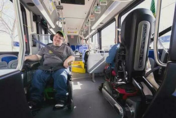 Two men in wheelchairs smiling and riding on an accessible public bus showcasing inspiring facts about inclusion.