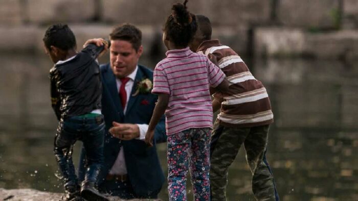 Man helping children play near water, capturing inspiring facts and moments better than watching the news.