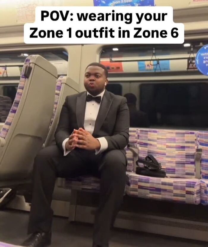 Man in a tuxedo sitting on a train seat with text about wearing a Zone 1 outfit in Zone 6, London memes humor.