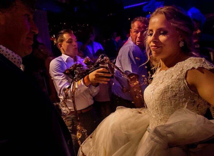 Man accidentally spills drink on bride’s wedding dress, capturing the split second before disaster hits in a funny moment.