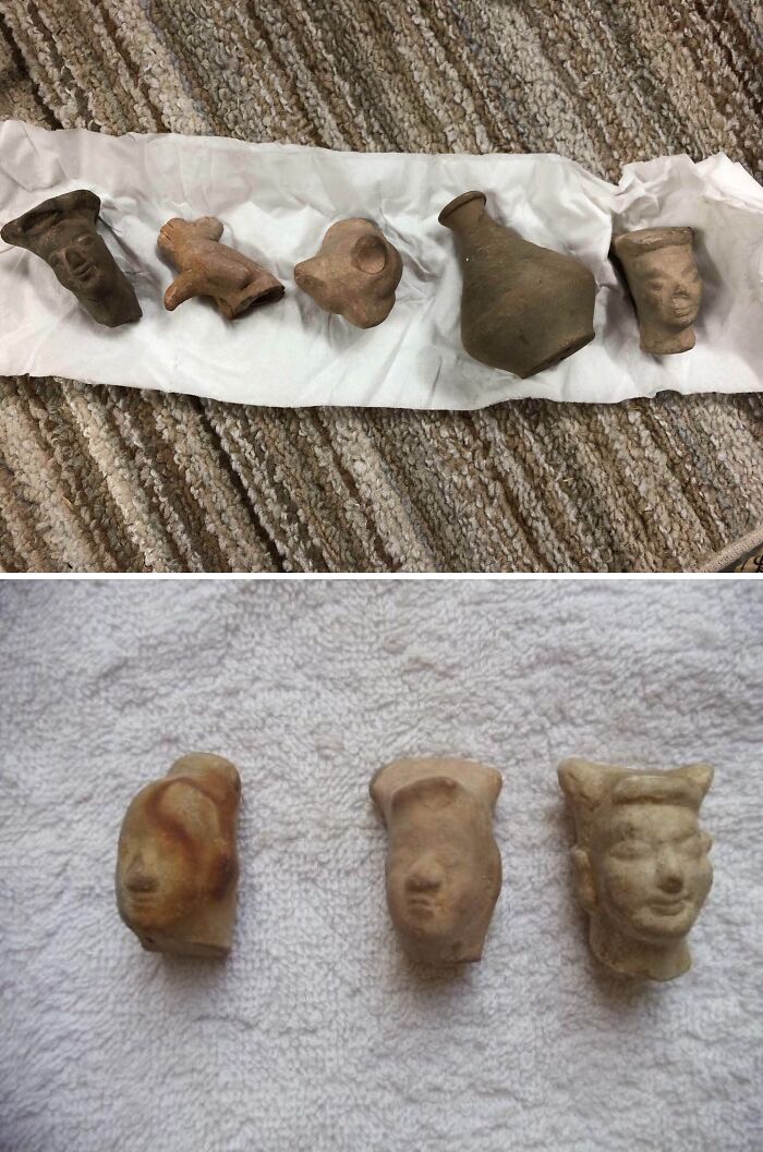 Old ancient artifacts and pottery fragments with carved faces, found but unidentified, laid out on fabric surfaces.