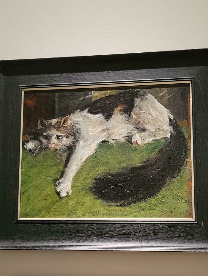 Painting of a medieval cat lying on a green surface, showcasing historic art and human fascination with cats.