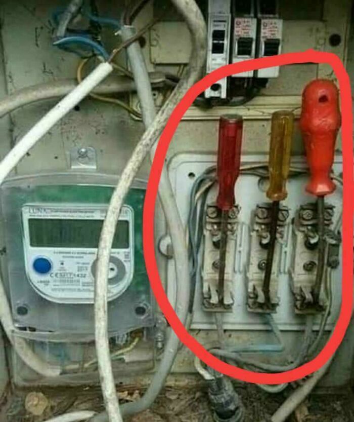 Old electrical panel with screwdrivers used as fuses, highlighting dangerous handling of electronics and soldering risks.