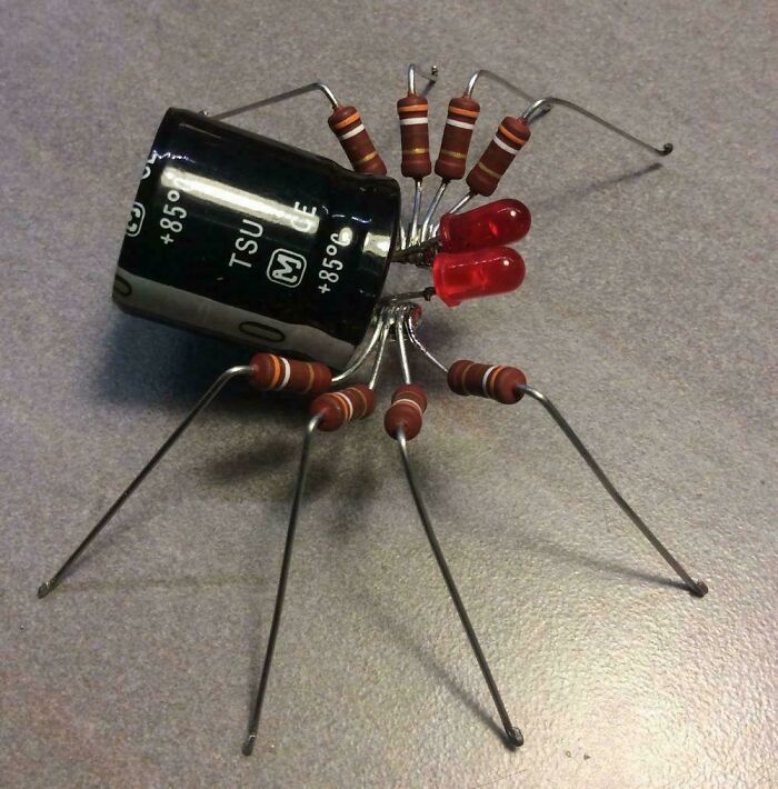 Creative electronics project made of capacitors, resistors, and LEDs arranged to resemble an insect with extended legs.