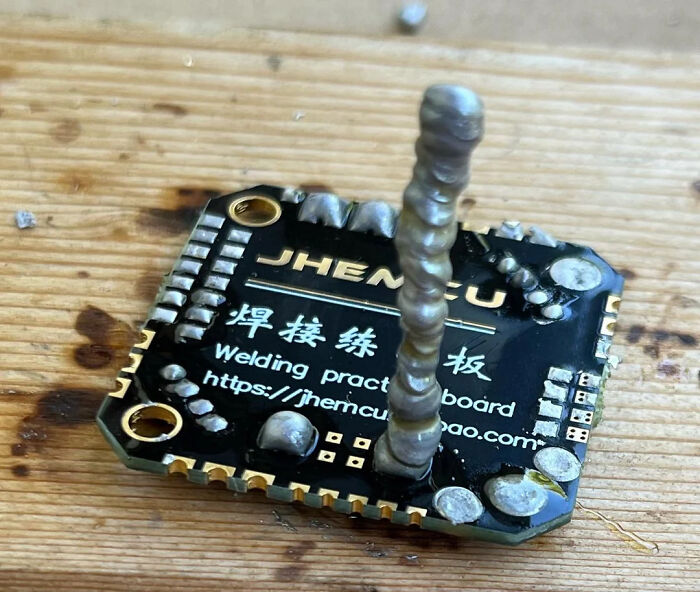 Close-up of a circuit board with a tall, uneven solder joint showing incorrect electronics handling.