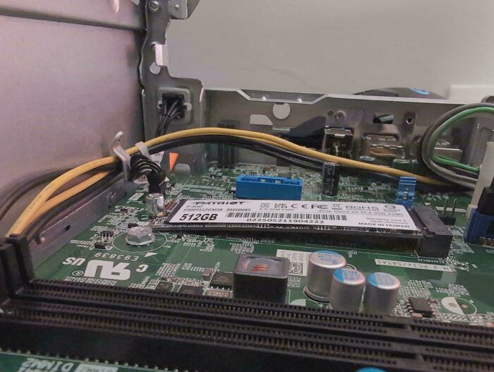 Close-up of a computer motherboard interior showing electronic components and wiring for soldering and repair tasks.