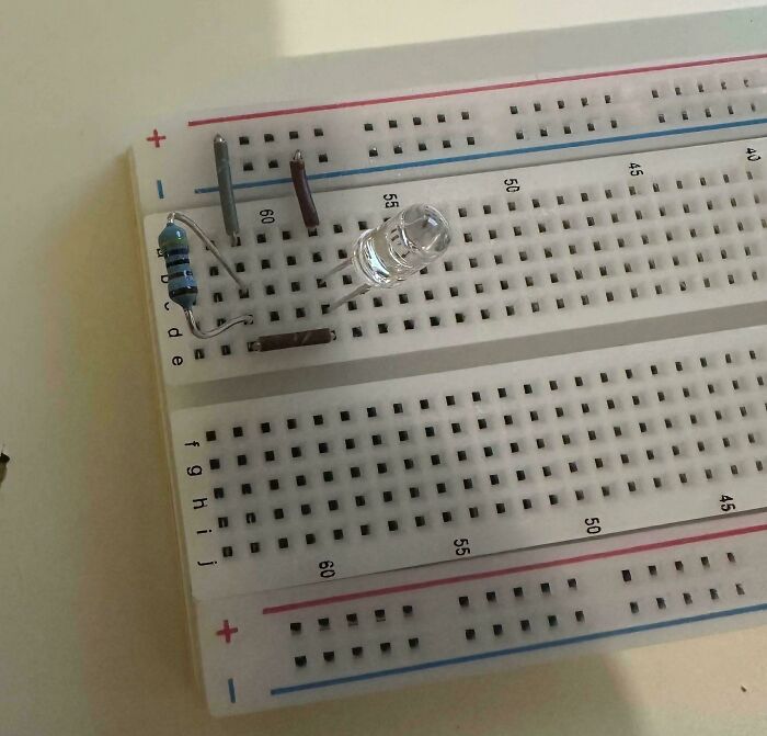 Breadboard with a resistor, LED, and jumper wires illustrating common mistakes in electronics soldering and handling.